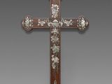une vieille croix en bois ornée de fleurs, sur fond gris