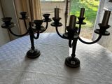 deux chandeliers noirs posés sur une table recouverte d'une nappe blanche
