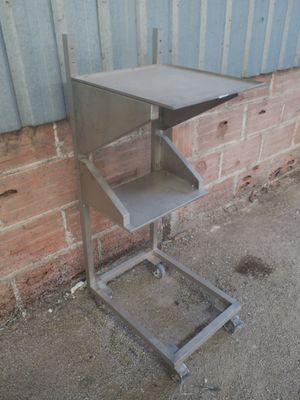 une table en métal surmontée d'une étagère, placée devant un mur de briques