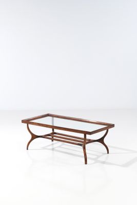 une table basse avec un plateau en verre, un piètement en bois et des pieds en métal