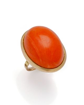 une bague orange, corail et or sur fond blanc