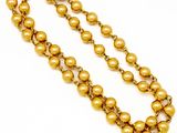 a close up of a gold beaded necklace on a white background