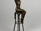 une statue en bronze représentant une femme assise sur un tabouret