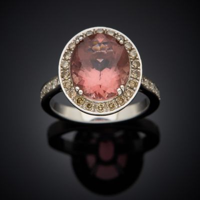 a close up of a ring with a pink stone surrounded by diamonds