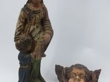 une statue représentant une femme tenant un oiseau à côté d'une statue représentant un homme