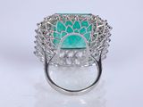 a close up of a ring with a green stone surrounded by diamonds