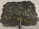a black fan with a painting of flowers on it