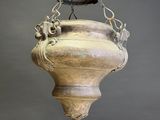 an old metal bell hanging from a chain on a gray wall