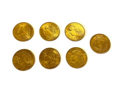 six pièces d'or sont disposées en ligne sur une surface blanche