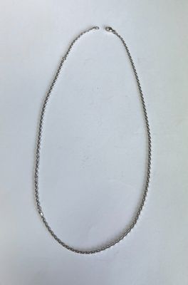 gros plan d'un collier en argent sur une surface blanche
