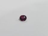 a round purple sapphire stone on a white surface