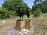 deux statues en bronze représentant un homme et une femme, posées sur des socles