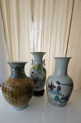 three vases sitting on a table with a curtain in the background
