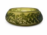 un bol vert orné de fleurs, posé sur une surface blanche
