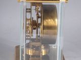 a gold clock with a glass case on a white surface
