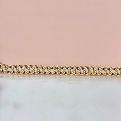 un gros plan d'un bracelet à chaîne en or posé sur une surface en marbre