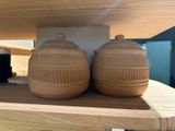 two wooden jars on a shelf with a wooden shelf behind them