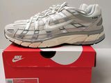 une paire de baskets blanches posée sur une boîte rouge