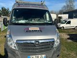 une photo montrant une camionnette argentée garée dans un champ, avec d'autres véhicules en arrière-plan