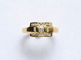 gros plan d'une bague en or avec des diamants sur une surface blanche