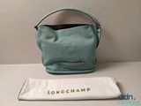 Le sac Longchamp est posé sur une table, à côté d'une serviette.