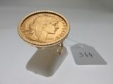 a gold ring with a coin on it and a price tag
