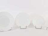 four white plates are lined up in a row on a white surface