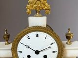 a white and gold clock sitting on top of a marble table