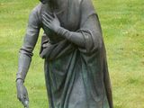 une statue représentant une femme assise dans l'herbe