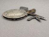 a silver coin and a pair of pliers on a table
