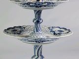 un présentoir à gâteaux bleu et blanc à trois étages, surmonté d'une figurine