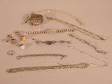 a lot of silver jewelry on a white surface