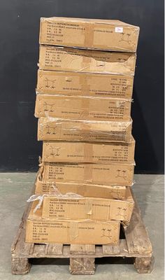 une pile de cartons posée sur une palette devant un mur noir
