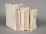 several books are stacked on top of each other on a gray surface