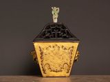 a yellow and black vase with a bird on top of it