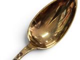 a gold spoon on a white surface with a white background
