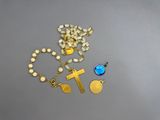 rosary, cross, and blue glass bead necklace on a gray surface