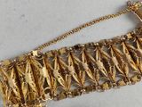 an image of a close up of a gold bracelet on a white surface