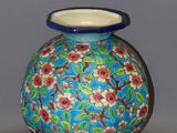 a blue vase with red flowers on it on a table