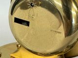 a gold clock that is sitting on a stand