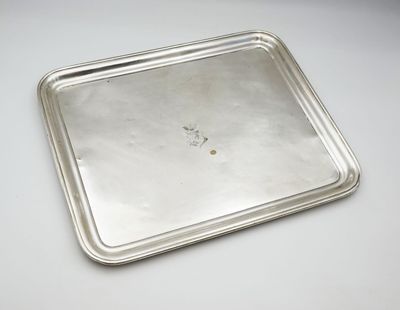 un vieux plateau en argent posé sur une table blanche, sur lequel se trouve un petit morceau de nourriture