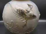 un vase blanc orné d'un oiseau, posé sur une table