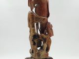 an old wooden statue of a man and woman sitting on a rock