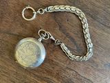 an image of a pocket watch on a table with a chain around it