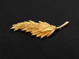 a gold leaf broochle on a black background