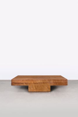 une table basse en bois avec un plateau carré, posée sur un sol en béton