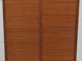 une armoire en bois à deux portes, avec un tiroir en dessous