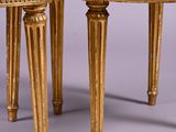 pair of gold painted chairs with wooden legs on a grey background