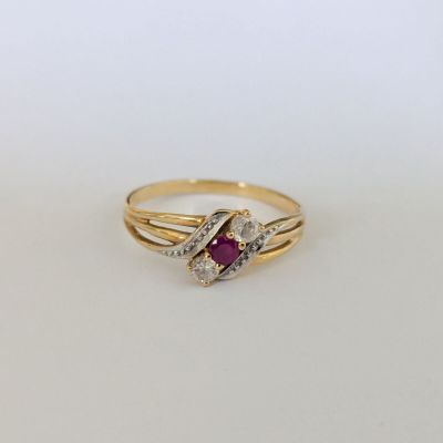 gros plan d'une bague en or avec un rubis et des diamants