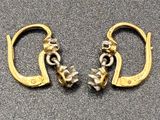 pair of gold plated earrings with flowers on them on a gray surface